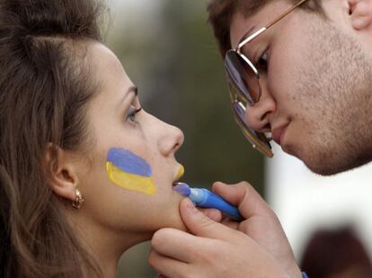 Un hombre pinta la cara de una mujer con los colores de la bandera ucraniana en Kharkiv, al este de Kiev, Ucrania.