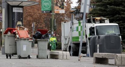Un trabajador municipal junto a cubos de basura rebosantes en otoño de 2013.