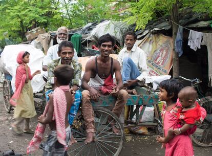 Un grupo de hombres del barrio de chabolas posan sentados encima de uno de los carritos que utilizan para recolectar y trasladar el material reciclable: papel, plástico o chatarra. Algunos de ellos también trabajan en la conducción de 'rickshaws' por solo unas rupias al día.