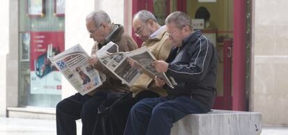 Un grupo de jubilados lee la prensa en una calle de Málaga. jubilados