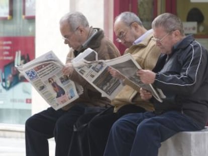 Un grupo de jubilados lee la prensa en una calle de Málaga. jubilados