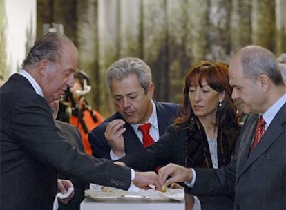 El Rey, acompañado del presidente de la Junta de Andalucía, Manuel Chaves, entre otros, moja pan en aceite en la inauguración hoy en Jaén de la exposición <i>Tierras de olivo</i>.