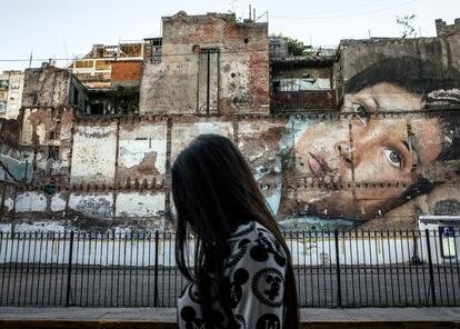 Una mujer camina por una calle del centro de Buenos Aires frente a un gran mural. La ciudad está repleta de arte urbano, a veces edificios enteros pintados. A menudo estas obras son políticas, muchas en referencia a la violencia de género, la injusticia y los desaparecidos.