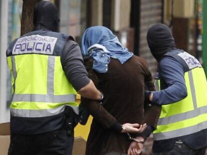 Dos policías acompañan a un detenido en el barrio de Vallecas (Madrid).