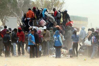 Refugiados de Ghana, huidos de Libia, se disponen a bajar sus pertenencias de un camión a su llegada al campamento levantado cerca de Ras el Jedir, durante una tormenta de arena, en Túnez.