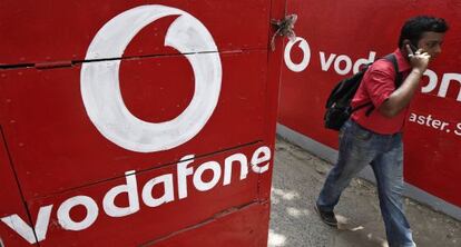 Un transe&uacute;nte camina junto a unos anuncios de Vodafone. 