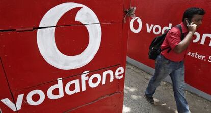 Un transeúnte camina junto a unos anuncios de Vodafone.