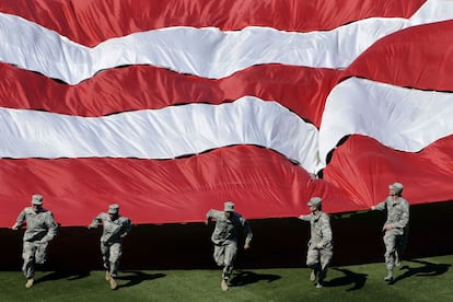 Miembros de las fuerzas armadas despliegan una bandera de Estados Unidos antes de un partido de béisbol entre los Filis de Filadelfia y los Medias Rojas de Boston. En Filadelfia.