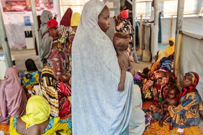 Una mujer con su hijo en brazos espera una consulta médica con MSF  en el centro de alimentación terapéutica ambulatoria de MSF Kofar Marusa, estado de Katsina, Nigeria, en junio de 2022.
