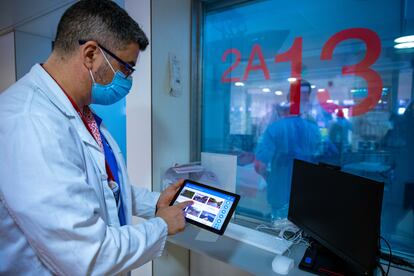 Un doctor maneja la tableta desde la que se controla tanto las imágenes como el color y los sonidos que puede percibir el paciente de las nuevas UCI mulisensoriales del Hospital de Bellvitge.