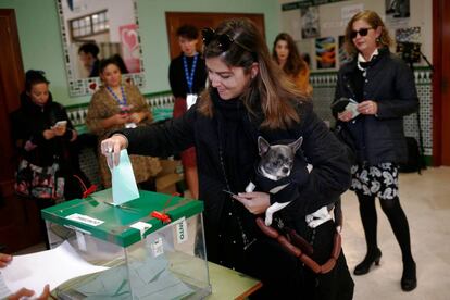 Una mujer acompañada por su mascota 'Torete' ejerce su derecho al voto en un colegio en Málaga.