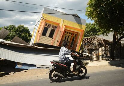 Un hombre conduce frente a una casa dañada por el terremoto, en Sira, Lombok, el 7 de agosto de 2018. 