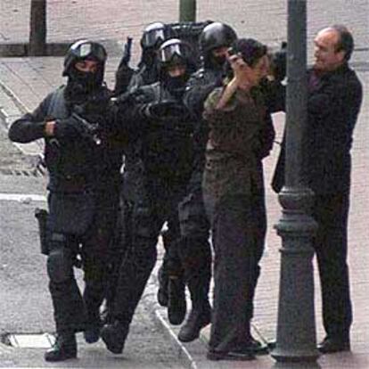 El atracador (segundo por la derecha) rodeado de policías tras ser detenido al asaltar una oficina bancaria en Madrid.