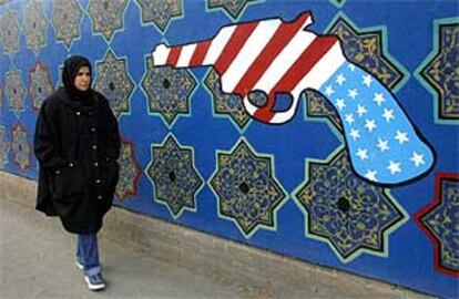 Una iraní pasa junto a un mural en el que la bandera de EE UU se ha convertido en una pistola.