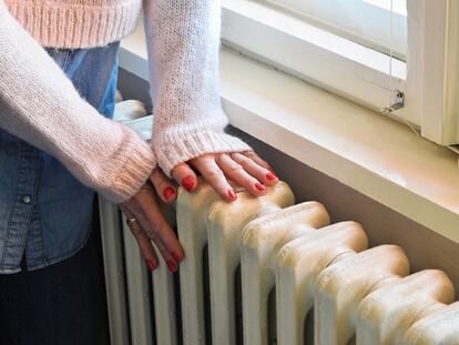 Una mujer comprueba la temperatura de un radiador.