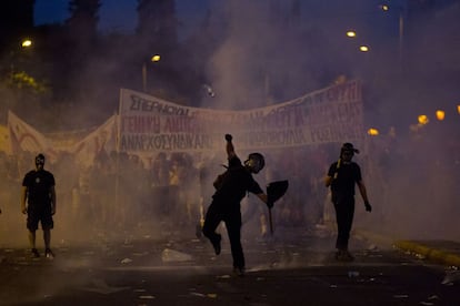 Un manifestante arroja una botella entre nubes de gases lacrimógenos.