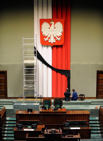 Unos operarios ajustan un lazo negro en un bandera de Polonia en el Parlamento, en señal de duelo por la muerte del presidente y de otros miembros de la élite del país que viajaban en el avión.