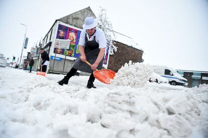 Un carnicero quita la nieve del camino fuera de su tienda en Auchterarder, en el centro de Escocia, este viernes mientras 'Eunice' trae fuertes vientos en todo el país.