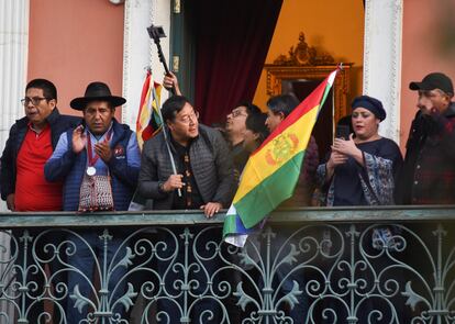 El presidente de Bolivia, Luis Arce, sostiene una bandera mientras se asoma a un balcón después de "denunciar la movilización irregular" de algunas unidades del ejército del país.