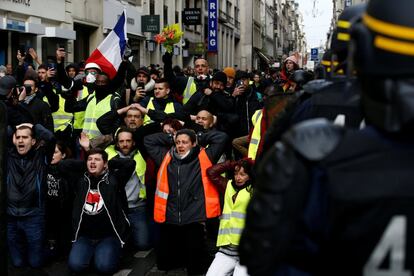 Un grupo de 'chalecos amarillos' se arrodilla frente a la policía antidisturbios durante la protesta de este sábado en la capital francesa.