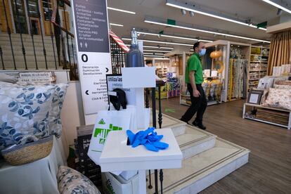 Un trabajador pasa junto a un punto donde se provee de guantes y de gel desinfectante en el interior de una tienda en Madrid, este martes.