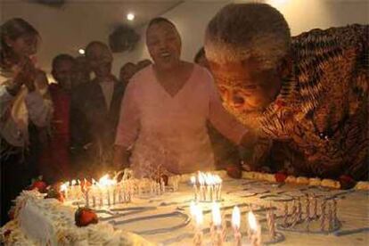 Nelson Mandela sopla las velas de la tarta en la celebración con sus colaboradores, en vísperas de su cumpleaños.
