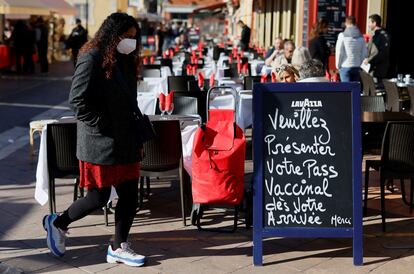 Un mujer pasa junto a un cartel en una terraza de Niza (Francia) con el siguiente mensaje: "Por favor, presente su pase vacunal cuando llegue".