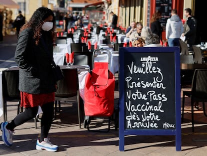 Un mujer pasa junto a un cartel en una terraza de Niza (Francia) con el siguiente mensaje: "Por favor, presente su pase vacunal cuando llegue".