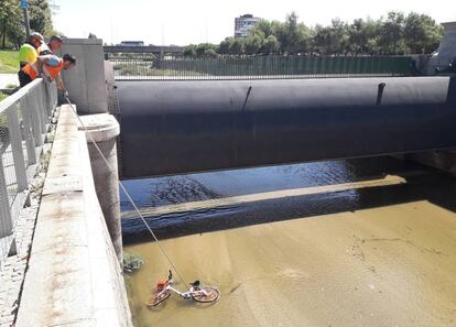 Varios operarios rescatan una bicicleta del río.