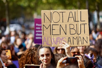 Una mujer lleva un cartel en inglés que reza "No todos los hombres, pero siempre un hombre" en una manifestación de apoyo a Gisèle Pelicot en París.