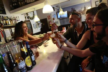 La camarera y varios clientes de un bar de Madrid brindando con sus cañas de cerveza.