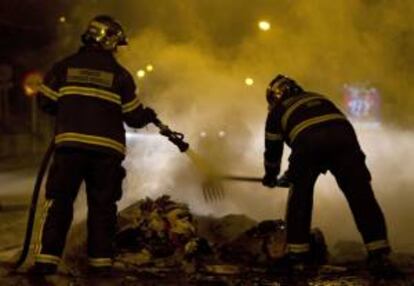 Miembros del cuerpo de bomberos, apagan uno de los muchos contenedores incendiados noche en la ciudad de Jerez.