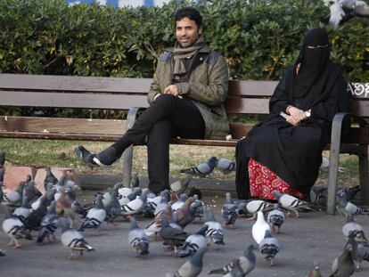 Una mujer ataviada con Burka sentada en el banco de un parque.