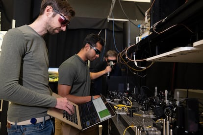 Da sinistra a destra, Jasper Palfree, Gautam Kavuri e Krister Shalm, davanti a un tavolo per la generazione ottica di numeri casuali presso il National Institute of Standards and Technology (NIST) a Boulder, Colorado.