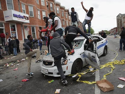 Manifestantes de Baltimore destroem um carro de pol&iacute;cia. 