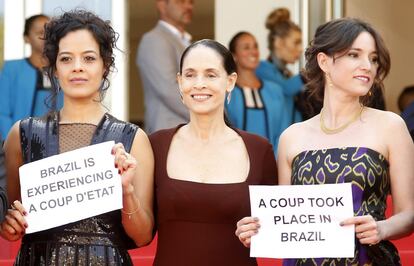 Maeve Jinkings, Sonia Braga e Emilie Lesclaux, do filme Aquarius, mostram cartazes em Cannes que dizem 'Brasil vive um golpe de Estado'.