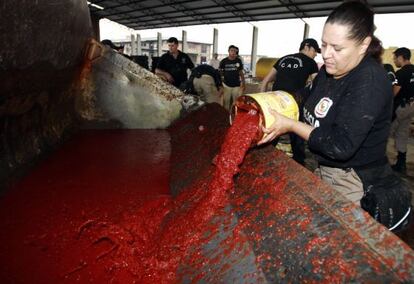 Una polic&iacute;a derrama tomates mientras inspecciona un cargamento de coca.