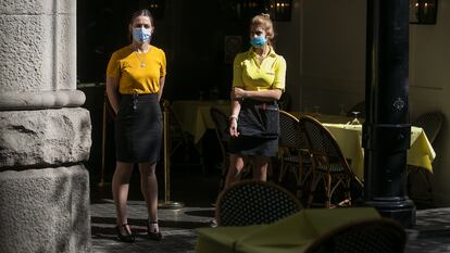 Two waiters at a sidewalk café in Catalonia, which has ordered the closure of all bars and restaurants from Friday.