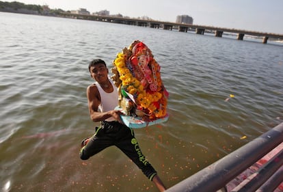 Un joven se lanza al agua sujetando una imagen del Dios Elefante en Ahmedabad (India), el 11 de septiembre de 2016.