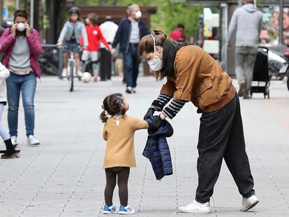 Una madre atiende a su hija mientras pasean por una calle de Madrid el pasado domingo.