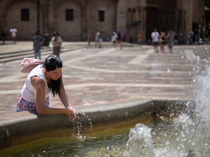 Una mujer se refresca en una fuente del centro histórico de Valencia.