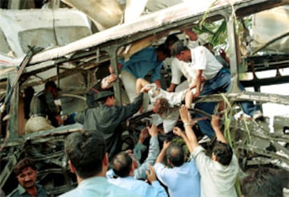 Un grupo de voluntarios traslada uno de los cadáveres de las víctimas del atentado contra un autobús en Karachi.