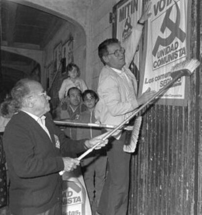Santiago Carrillo y Julián Ariza pegan un cartel de su partido.