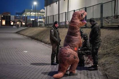 Un animador infantil disfrazado de dinosaurio habla con soldados polacos en el cruce fronterizo de Medyka (Polonia). Naciones Unidas ha afirmado que el de Ucrania es el éxodo más rápido en Europa desde la II Guerra Mundial.