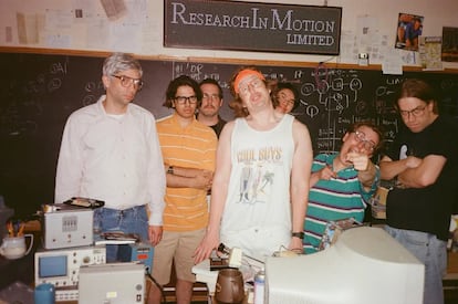 Imagen de la película 'BlackBerry', con los ingenieros que inventaron el aparato, liderados por Mike Lazaridus (encarnado por Jay Baruchel), a la izquierda, y Doug Fregin (Matt Johnson), con cinta en el pelo.