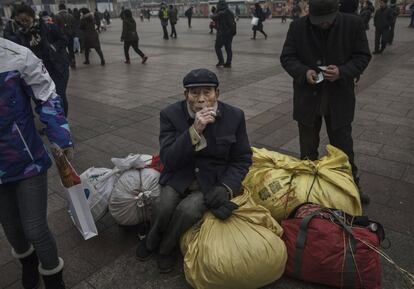 Un hombre descansa sobre sus bolsas de equipaje a las afueras de la estación de Pekín.