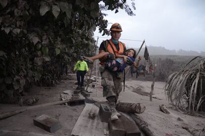 Un treballador dels equips de rescat de Guatemala ajuda una nena a El Rodeo, Escuintla (Guatemala), el 3 de juny.