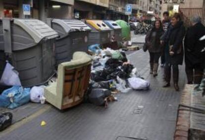 La basura acumulada en algunos contenedores, como éste de una céntrica calle de la ciudad, dificulta el paso de peatones en esta cuarta jornada de huelga de la empresa del servicio de recogida.