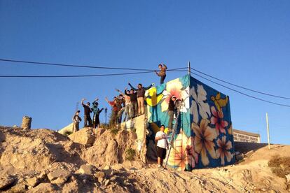 Jóvenes de El Maclovio posan con su mural al atardecer.