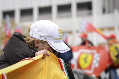 Uma mulher, com o boné bordado com o nome do ex-piloto, chora em frente ao hospital francês de Grenoble.